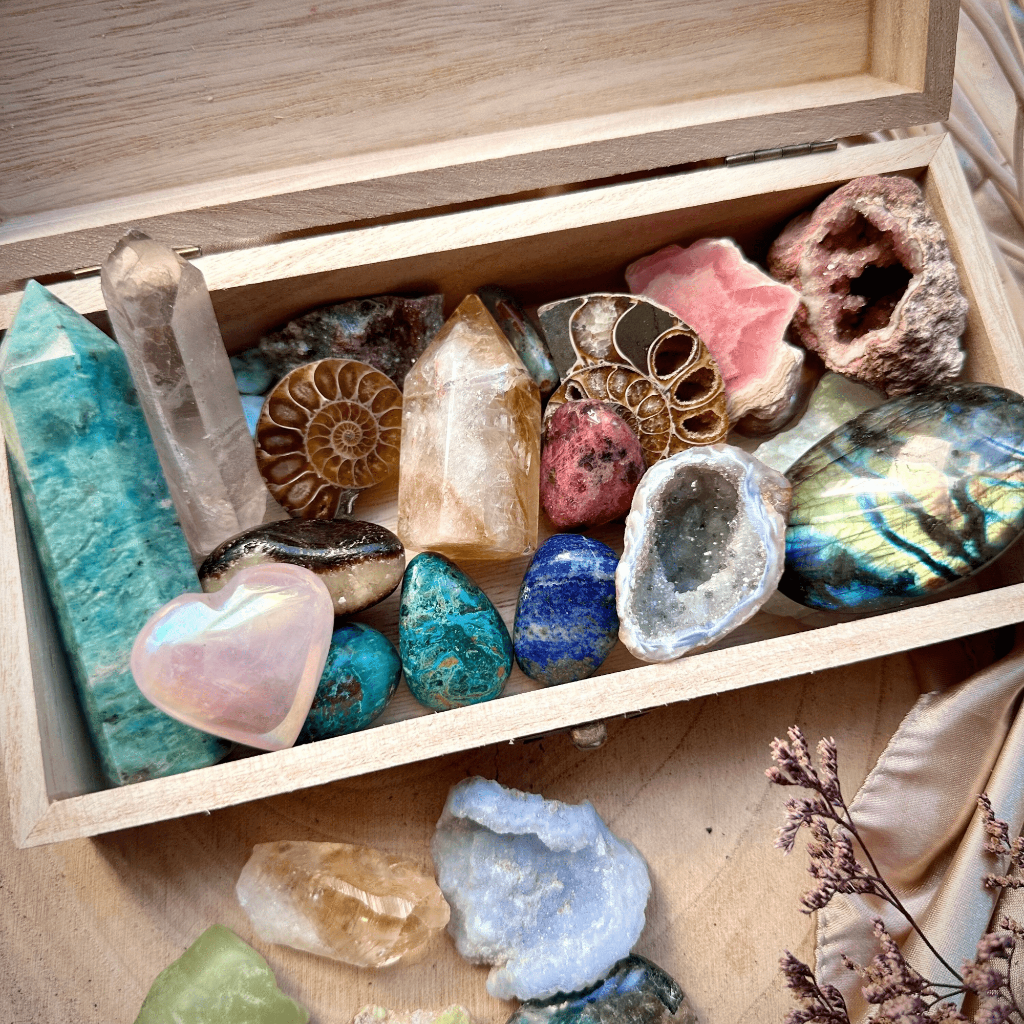 A variety of crystals and gemstones placed in a wooden box.