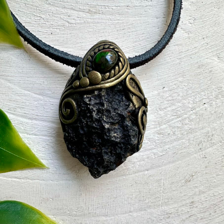 Necklace with a pendant featuring a green stone and bronze detailing on a light background.