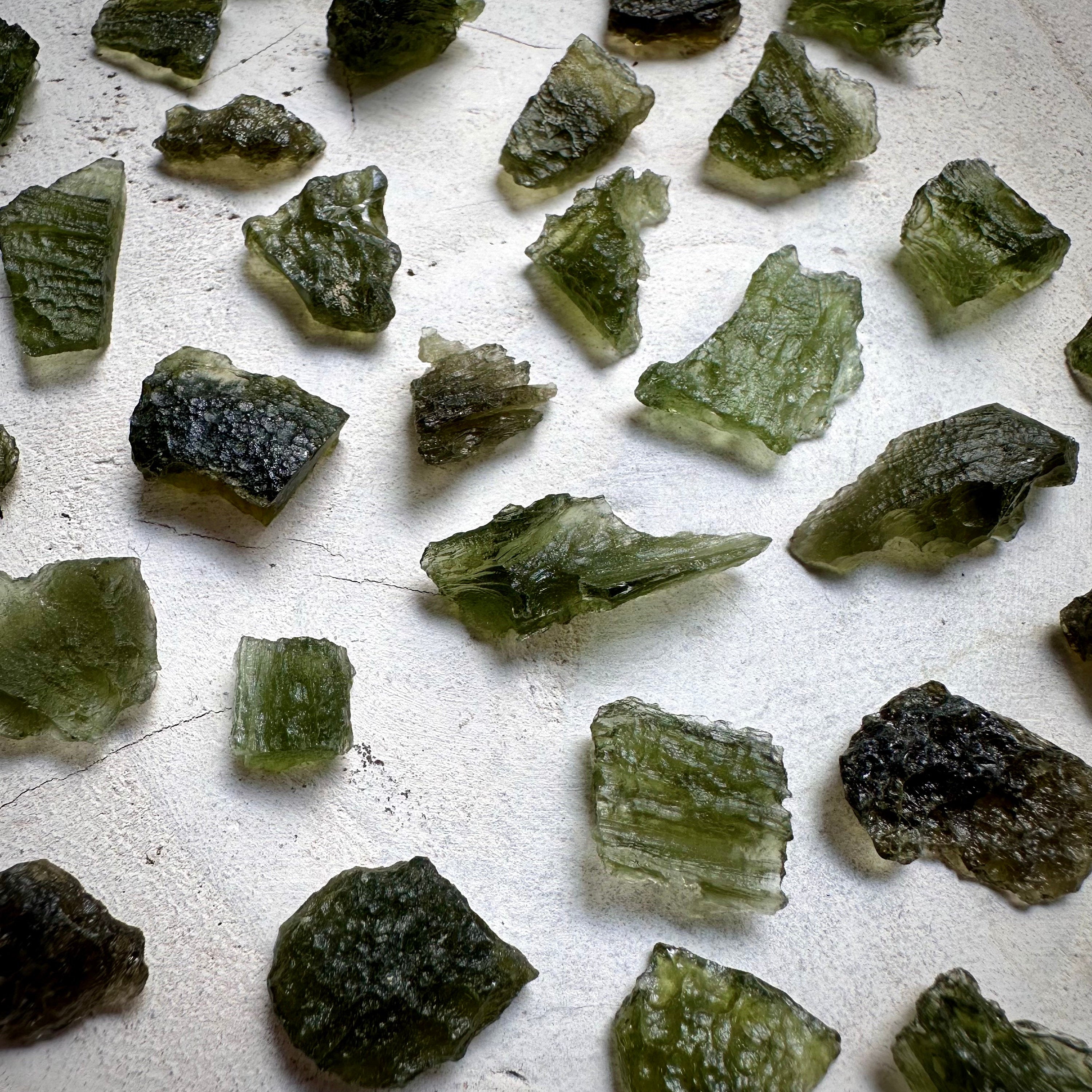 Raw Moldavite Crystals on white wooden background.