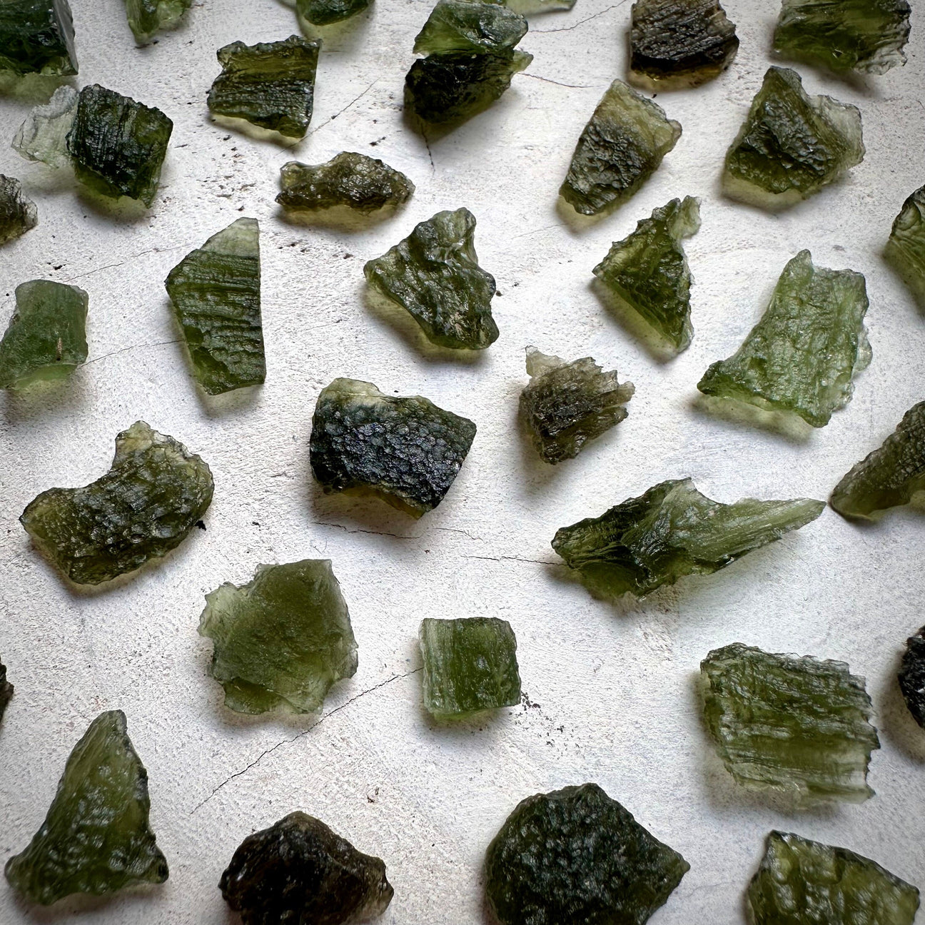 Natural Moldavite Crystals Laying on white wood
