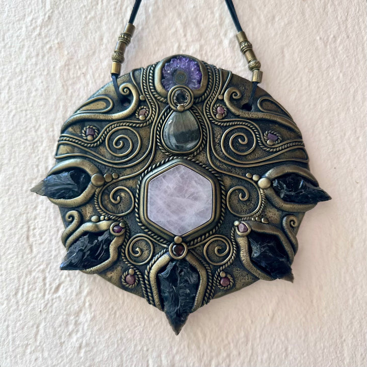 Decorative pendant with intricate designs on a white background