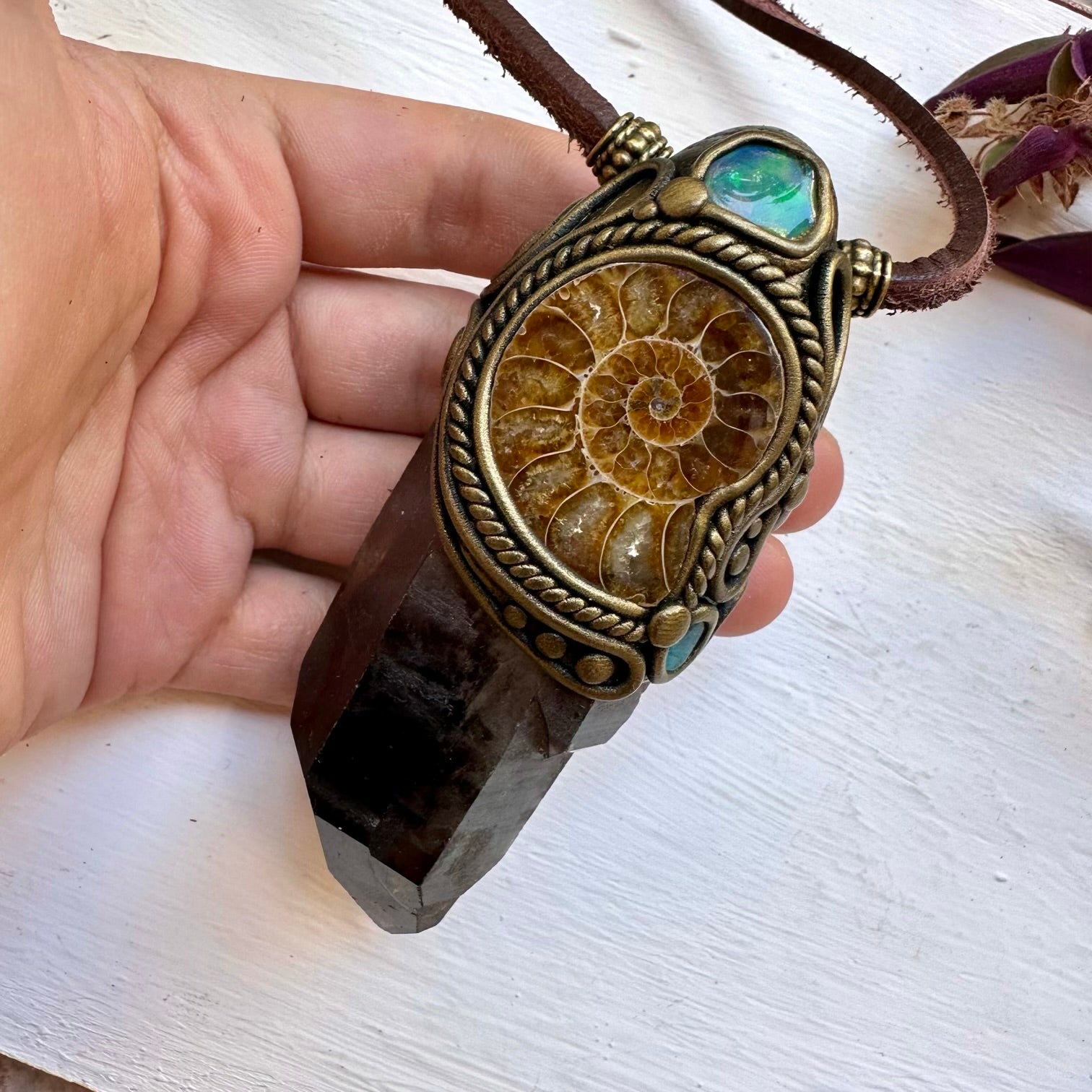 Necklace / Crystal Wnad with a decorative pendant held by a hand on a white surface