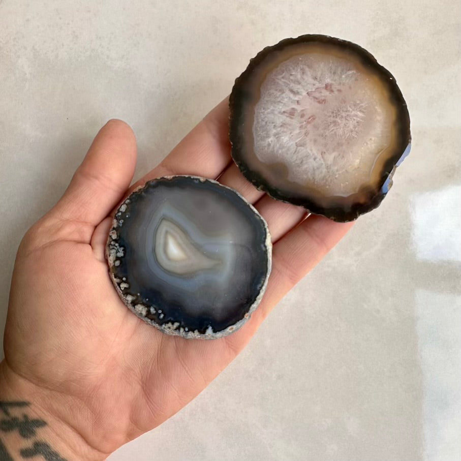Two agate stones held in a hand against a neutral background