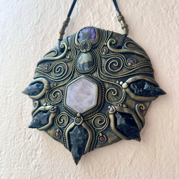 Decorative pendant with intricate designs on a plain background