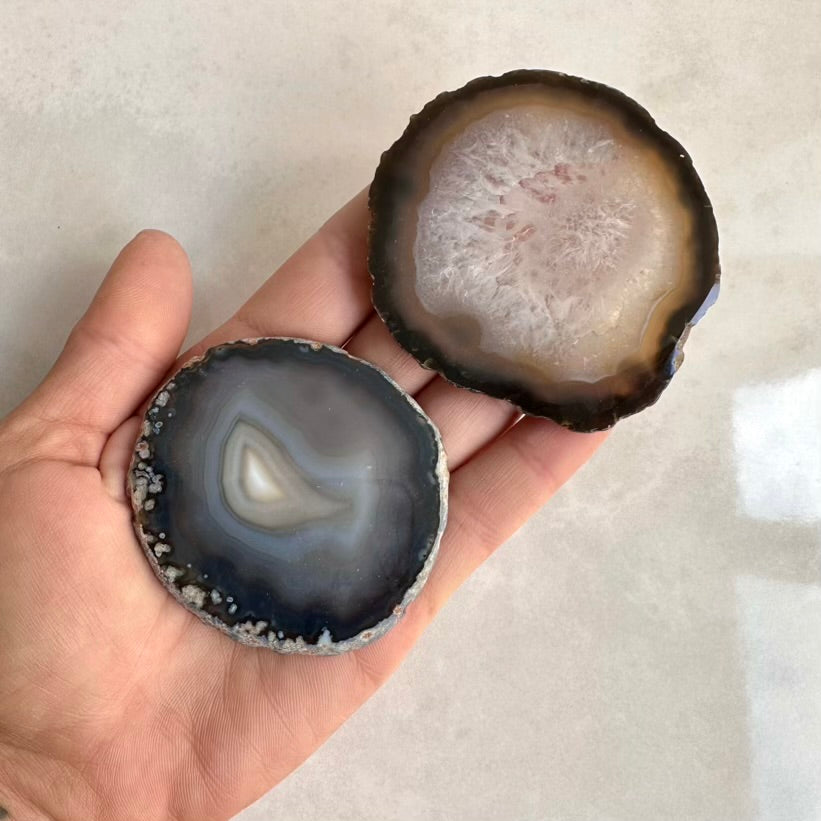 Two agate stones held in a hand against a neutral background