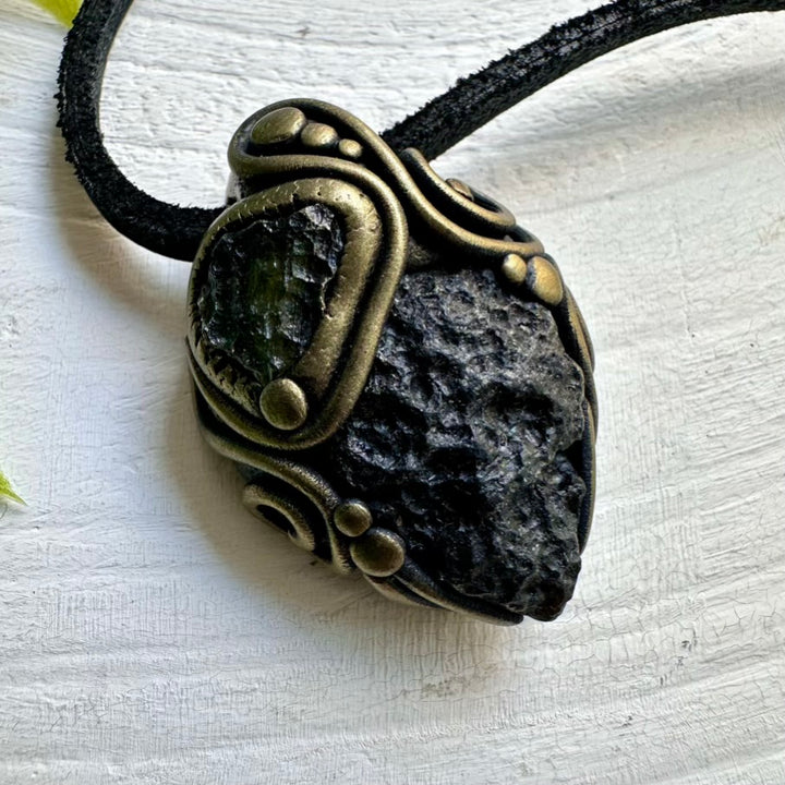 Necklace with a pendant featuring a dark stone and gold accents on a white background