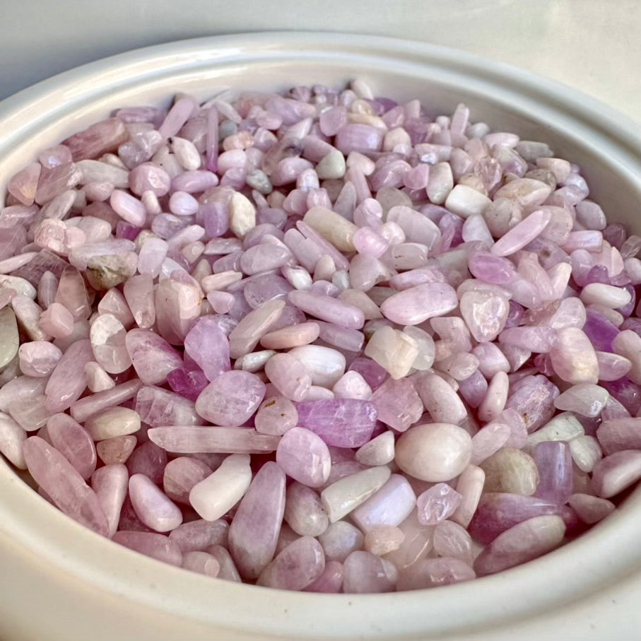 Pink kunzite gemstone chips in a white container