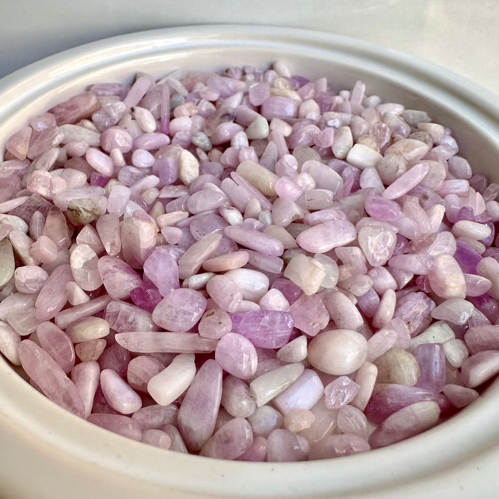 Pink kunzite gemstone chips in a white container