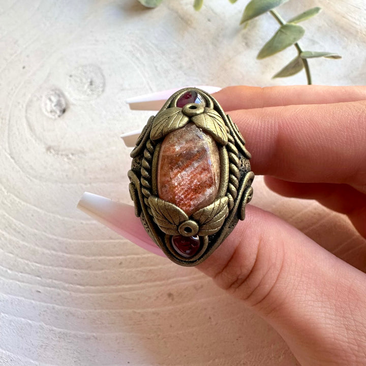 Handmade healing crystal ring featuring glowing Sunstone and Rhodolite Garnet.