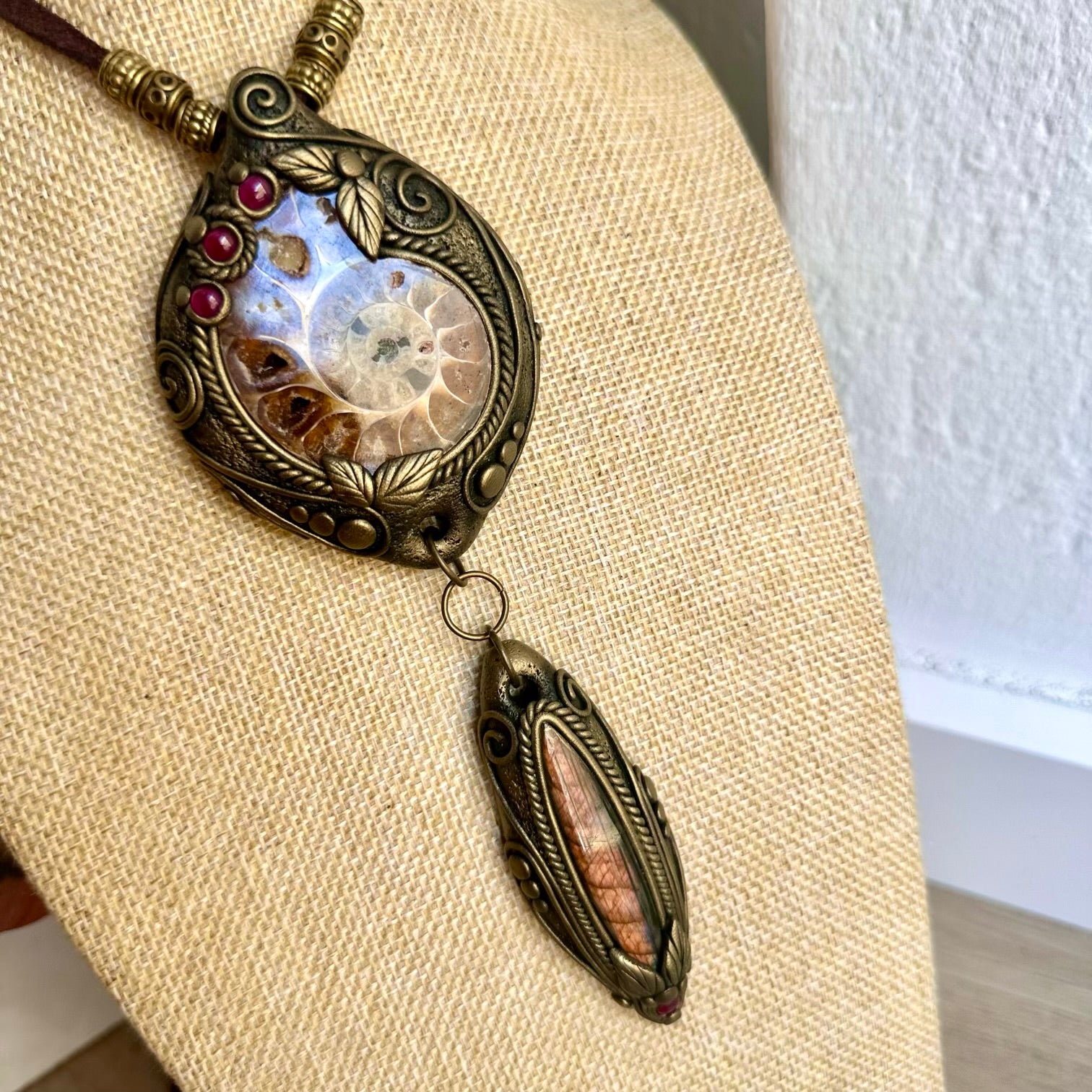 Handmade statement crystal necklace featuring a natural Ammonite with Labradorite and Rhodolite Garnet, a one of a kind fossil gemstone talisman designed for grounding, intuition, transformation and personal growth.