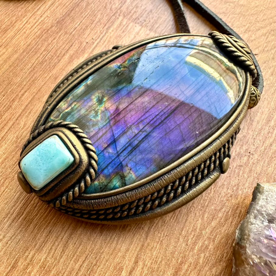 Necklace with a large, purple labradorite stone and antique bronze -tone setting on a wooden surface