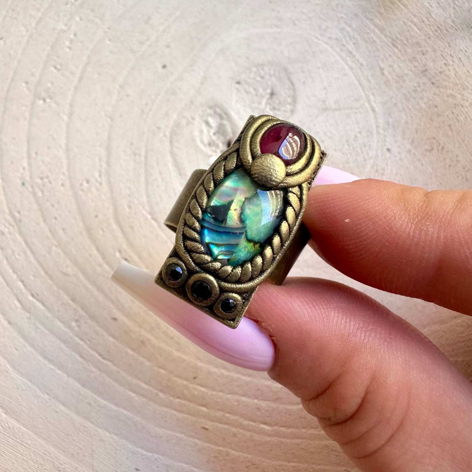 Unique ring featuring iridescent Abalone with rich red Rhodolite Garnet and deep blue Sapphire.