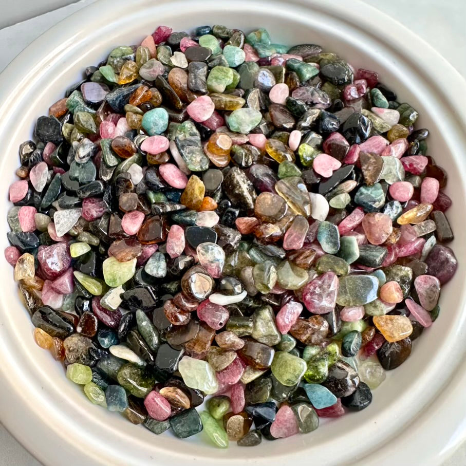 Assorted multicolored gemstones in a white bowl