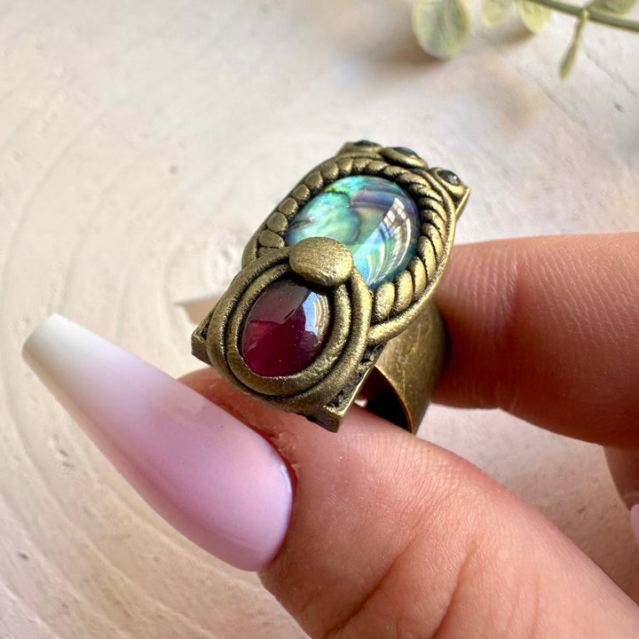 Handmade jewelry featuring an iridescent Abalone shell with Rhodolite Garnet and Blue Sapphire accents.