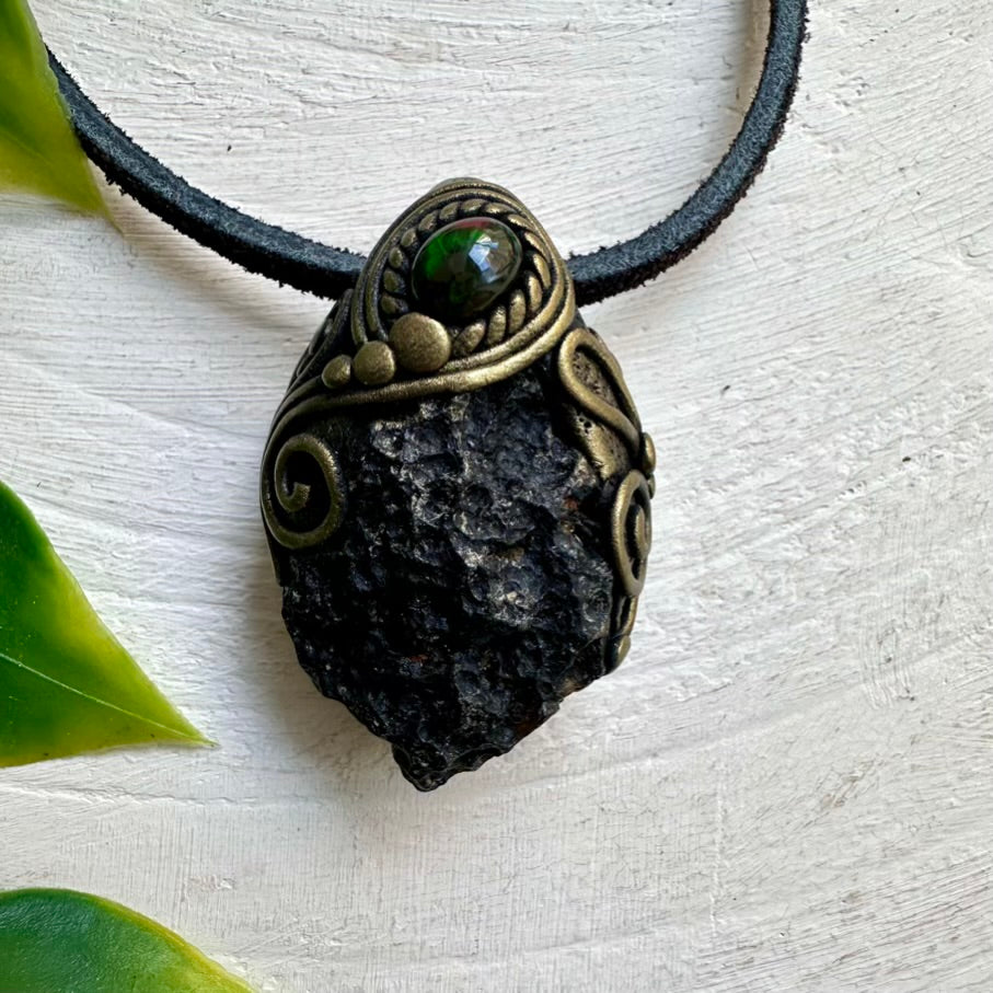 Necklace with a pendant featuring a green stone and bronze detailing on a light background.