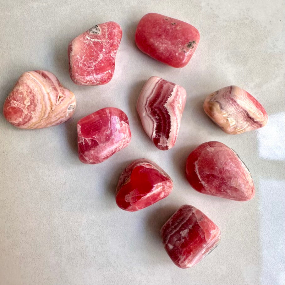 Pink and white polished rhodochrosite stones on a light gray background
