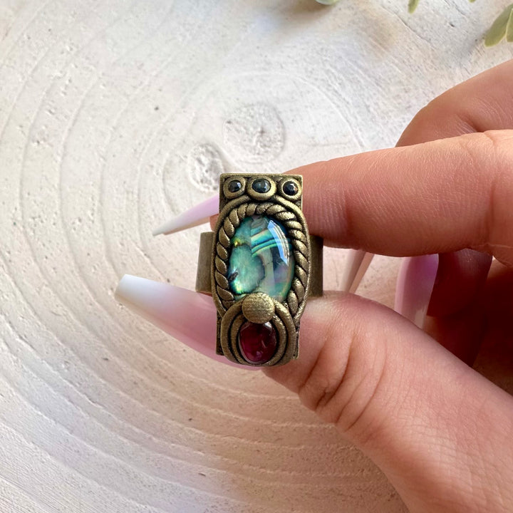 Artisan ring showcasing colorful Abalone Seashell with natural Garnet and Sapphire gemstones.