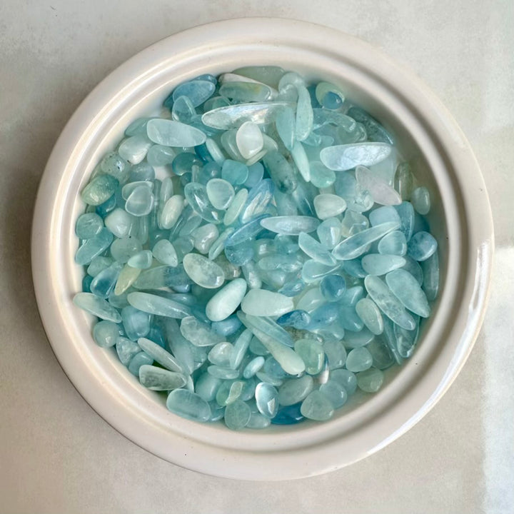 White bowl filled Aquamarine healing crystals on a white background