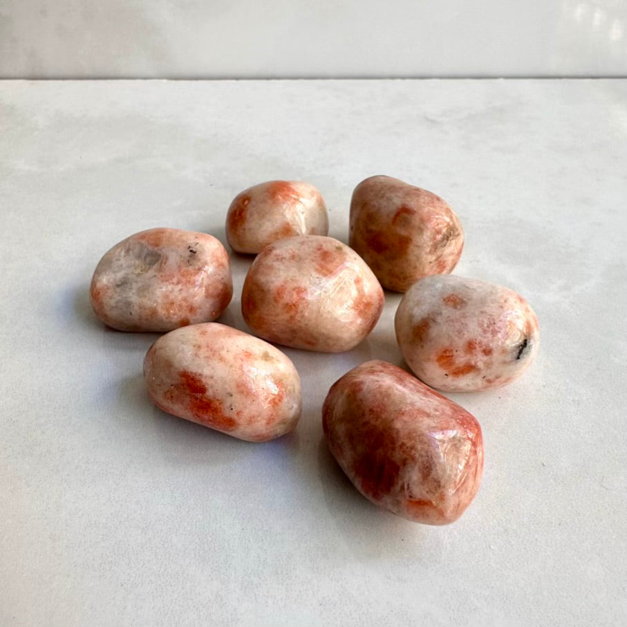 Group of polished sunstone crystal stones on a white marble surface