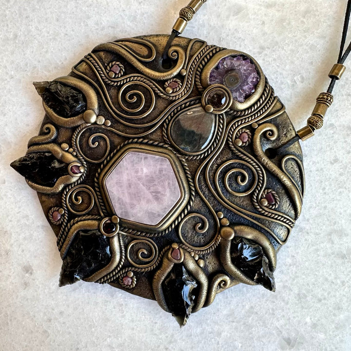 Decorative crystal pendant with intricate designs and gemstones on a textured surface