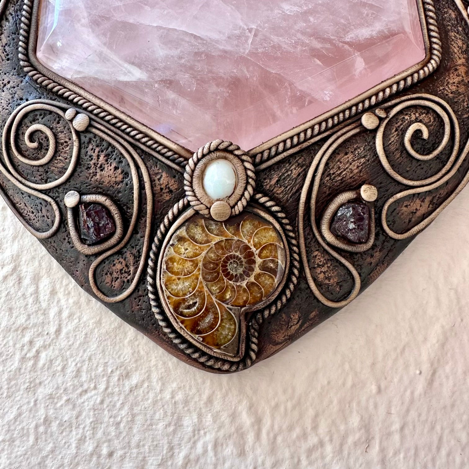 Decorative stone with ornate metalwork and a central gemstone on a textured white background
