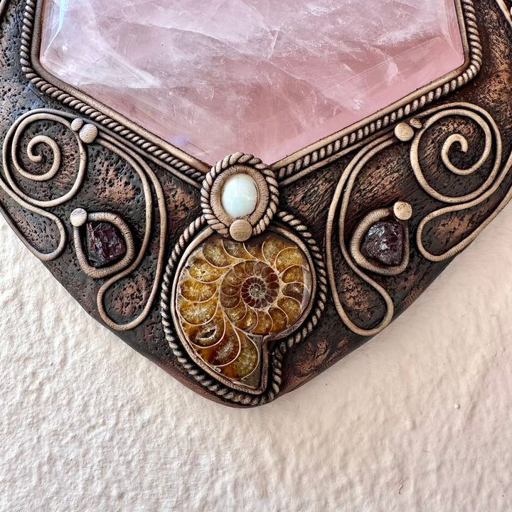Decorative stone with ornate metalwork and a central gemstone on a textured white background