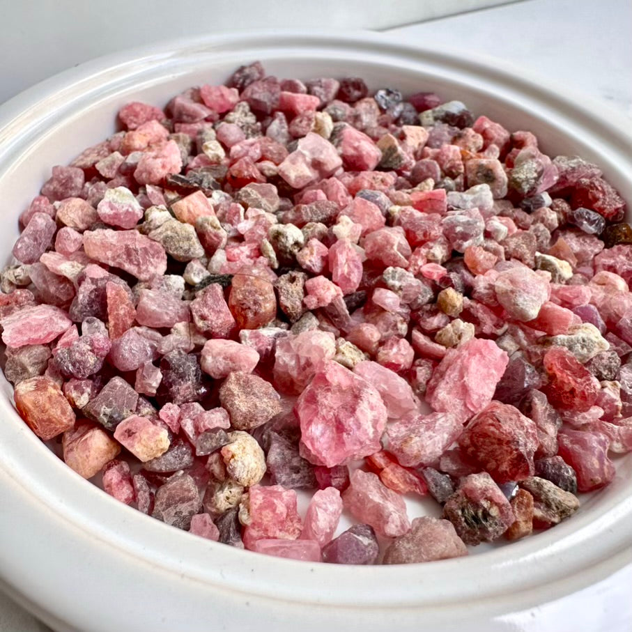 Raw Spinel crystals lot from Tanzania in a white bowl on a white background