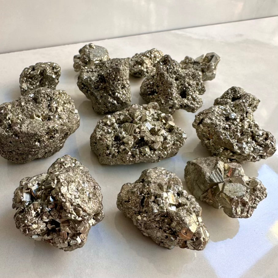 Collection of metallic pyrite crystals on a white surface