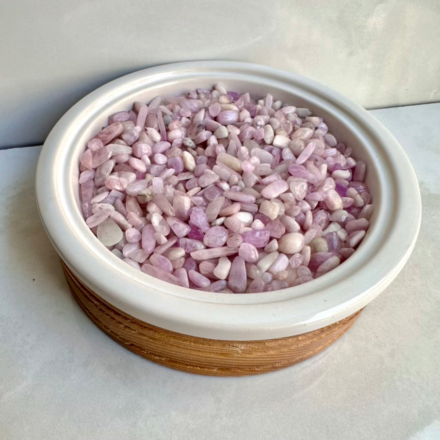 Small bowl filled with natural pink kunzite stones on a light surface