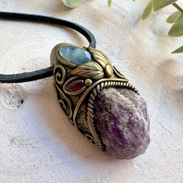 Natural gemstone pendant featuring Aquamarine and Rhodolite Garnet alongside a raw Scapolite crystal.