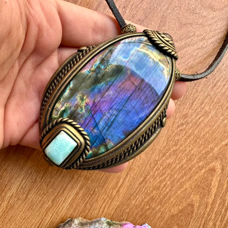 Purple Labradorite Larimar and Amethyst Necklace  held by a hand on a wooden surface
