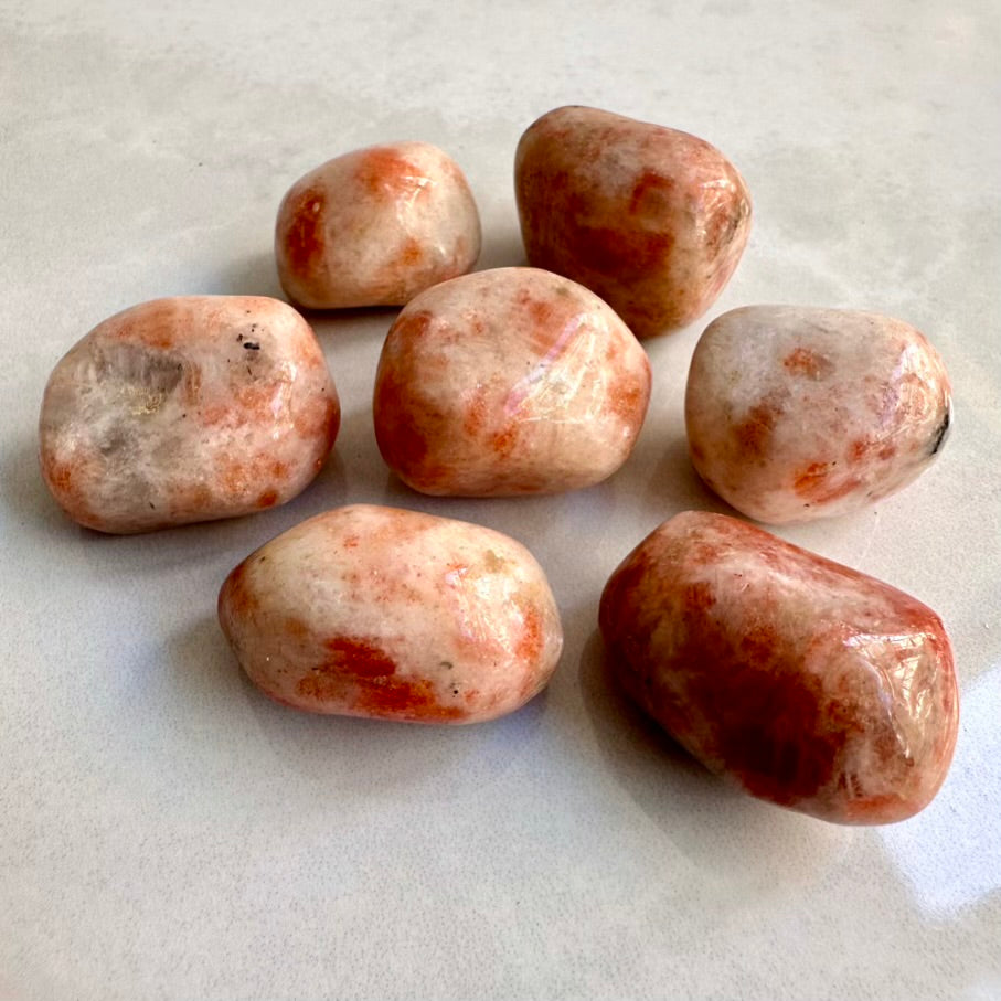 Set of eight Natural polished Sunstone gemstones on a light gray background