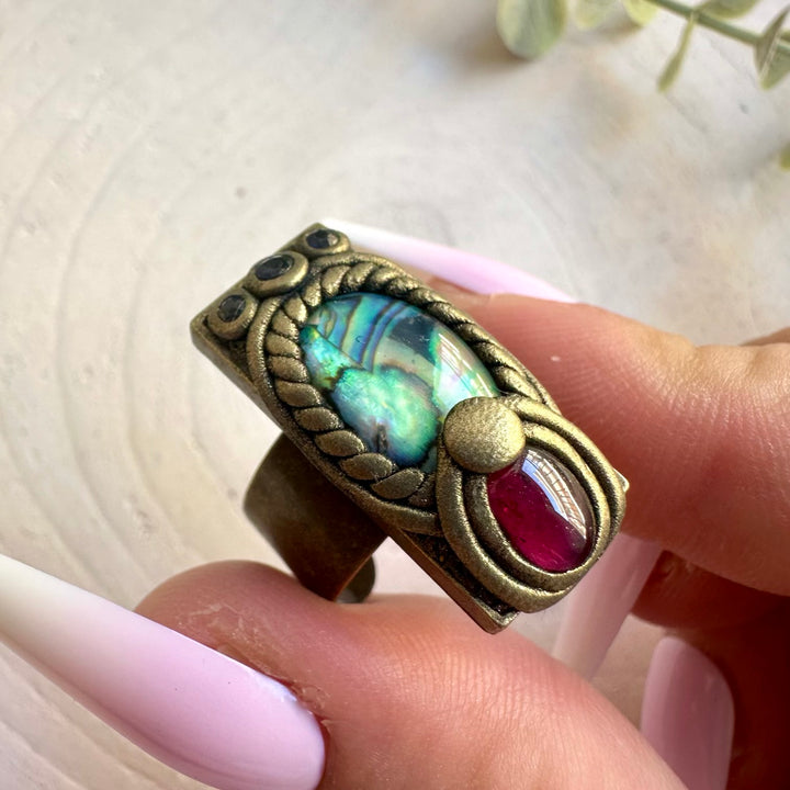 One of a kind handmade ring combining colorful Abalone Seashell with natural blue and red gemstones.
