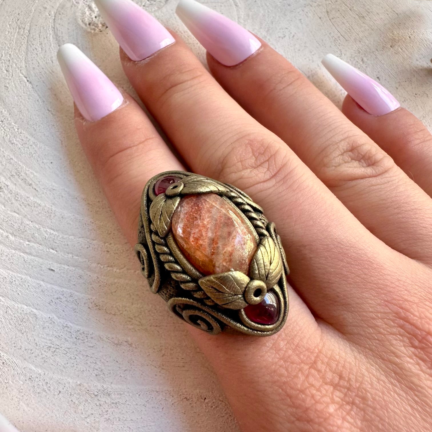 One of a kind Sunstone ring with deep red Rhodolite Garnet accents.