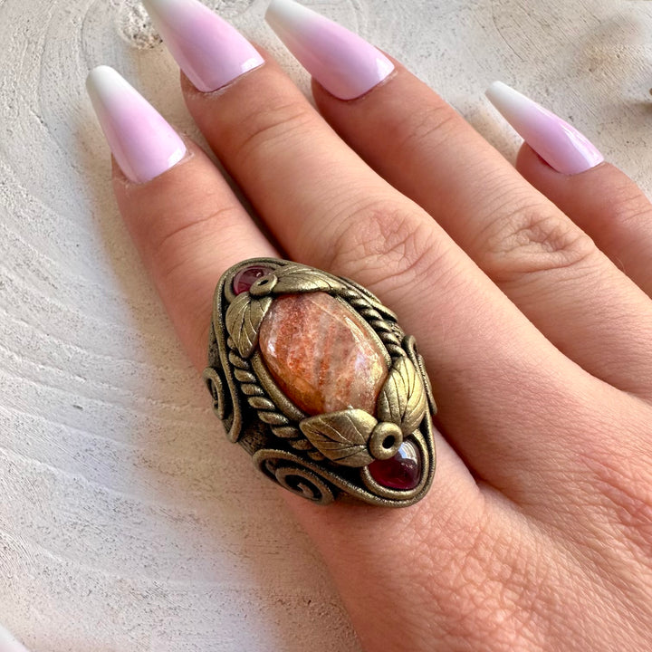 One of a kind Sunstone ring with deep red Rhodolite Garnet accents.
