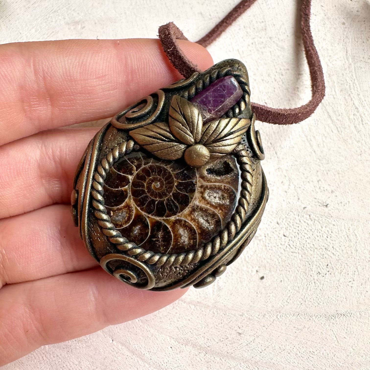 Protection amulet necklace featuring healing crystals Ruby gemstone and natural Ammonite fossil pendant.