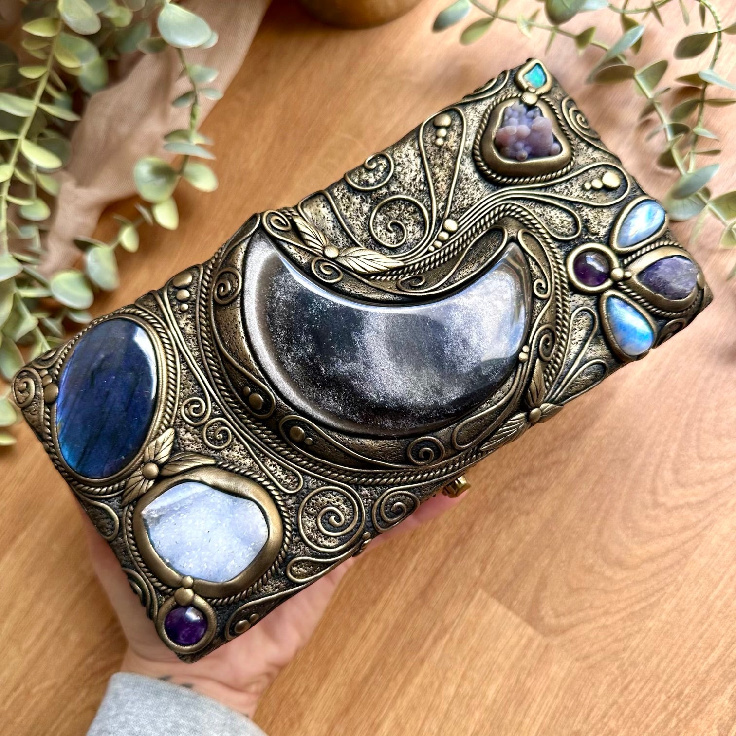 Close up of silver sheen obsidian moon centerpiece on a crystal decorated wooden box