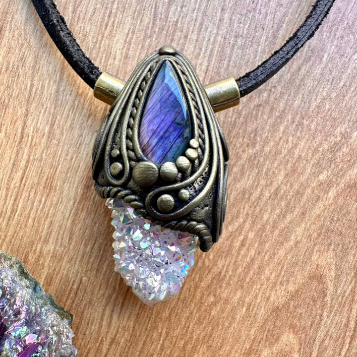 Necklace with a decorative pendant featuring a blue stone and druzy crystal on a wooden surface.