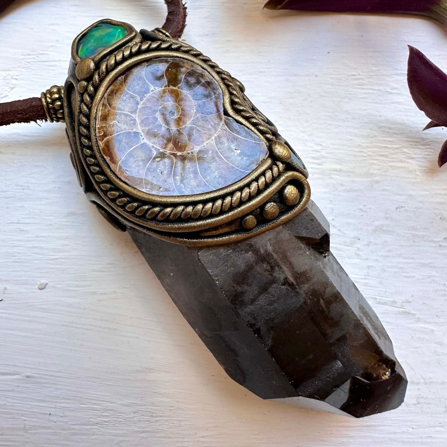 Decorative crystal pendant with ornate claywork on a white surface