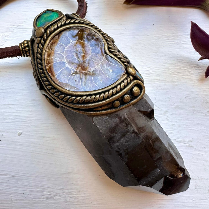 Decorative crystal pendant with ornate claywork on a white surface