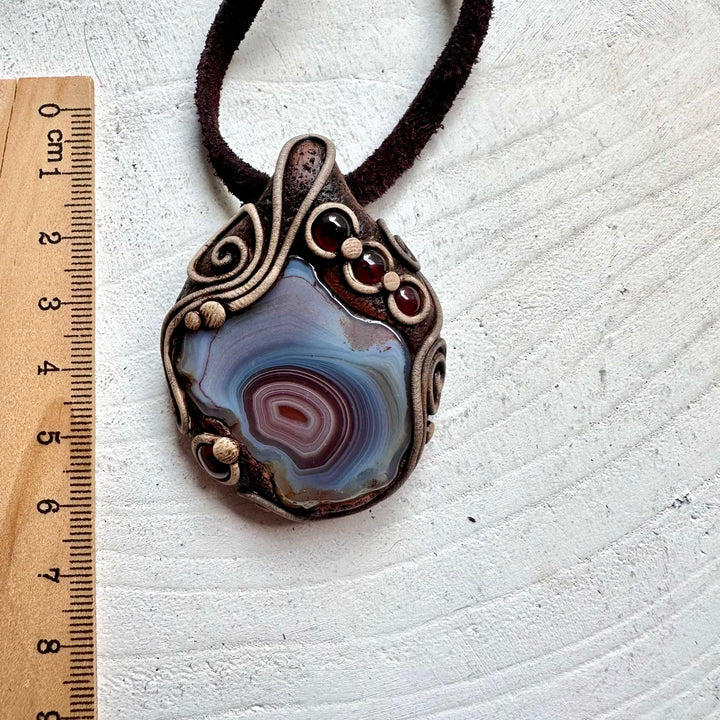 One of a kind crystal pendant handcrafted with Botswana Agate and deep red Rhodolite Garnet.