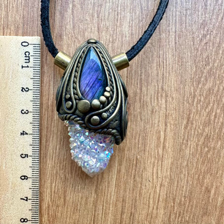 Necklace with purple labradorite and aura quartz crystal on a wooden surface next to a ruler