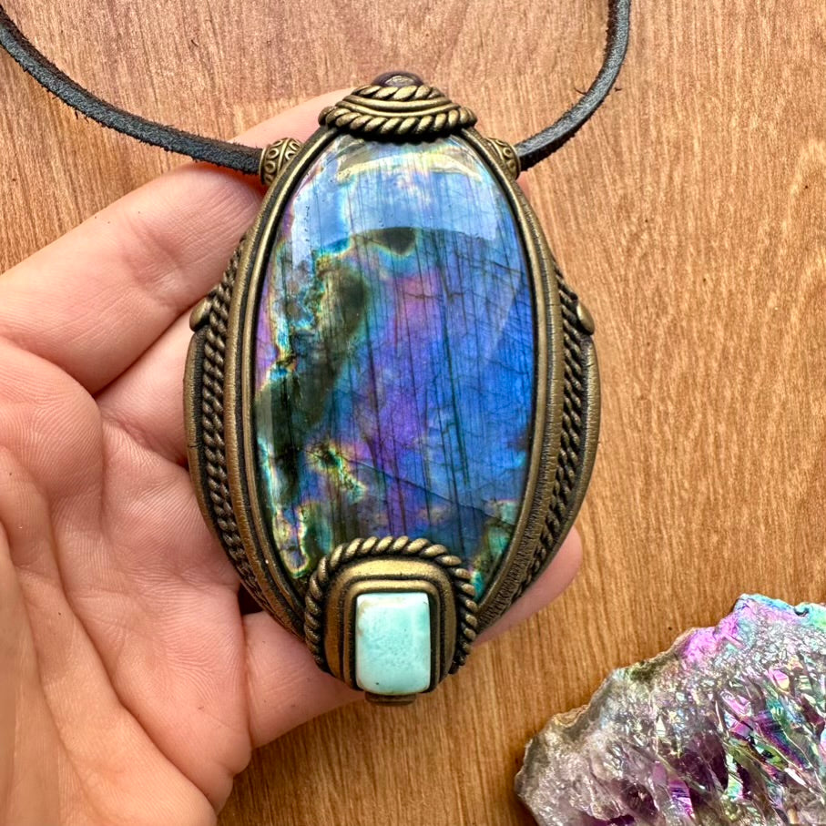 Purple Labradorite Larimar and Amethyst Necklace held by a hand on a wooden surface