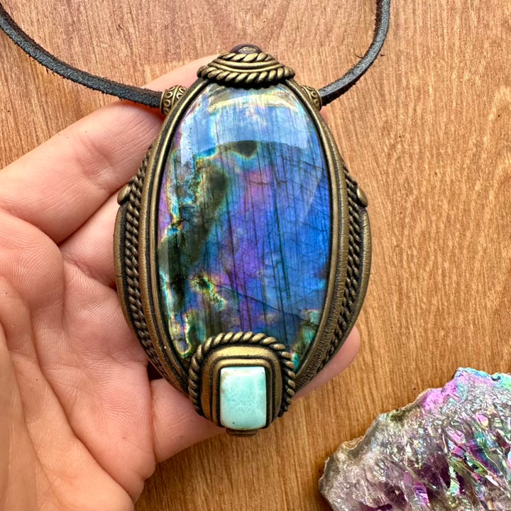 Purple Labradorite Larimar and Amethyst Necklace held by a hand on a wooden surface