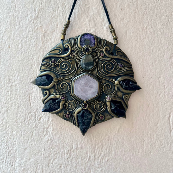 Decorative wall hanging with intricate design and stones on a white wall