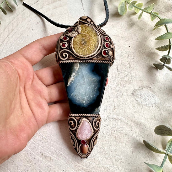 Handmade Agate with Ammonite, Raw Morganite, Ethiopian Opal and Rhodolite Garnet crystal wand / pendant necklace, a one of a kind healing crystal jewelry piece combining earthy Agate and an ancient Ammonite with delicate Morganite, colorful Ethiopian Opal and rich Rhodolite Garnet. This unique spiritual gemstone talisman is inspired by traditional associations of grounding, stability, ancient wisdom, love, compassion, creativity, confidence and transformation.