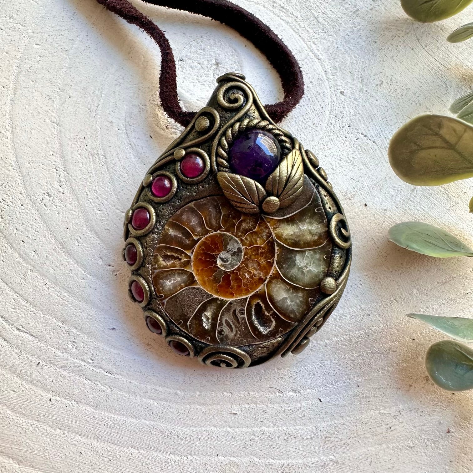 Handmade Ammonite healing crystal necklace featuring Amethyst and Rhodolite Garnet, a one of a kind gemstone pendant combining an ancient natural fossil with rich purple and deep red crystals. Artisan spiritual jewelry crafted with genuine natural materials, inspired by transformation, inner peace, intuition and personal strength.