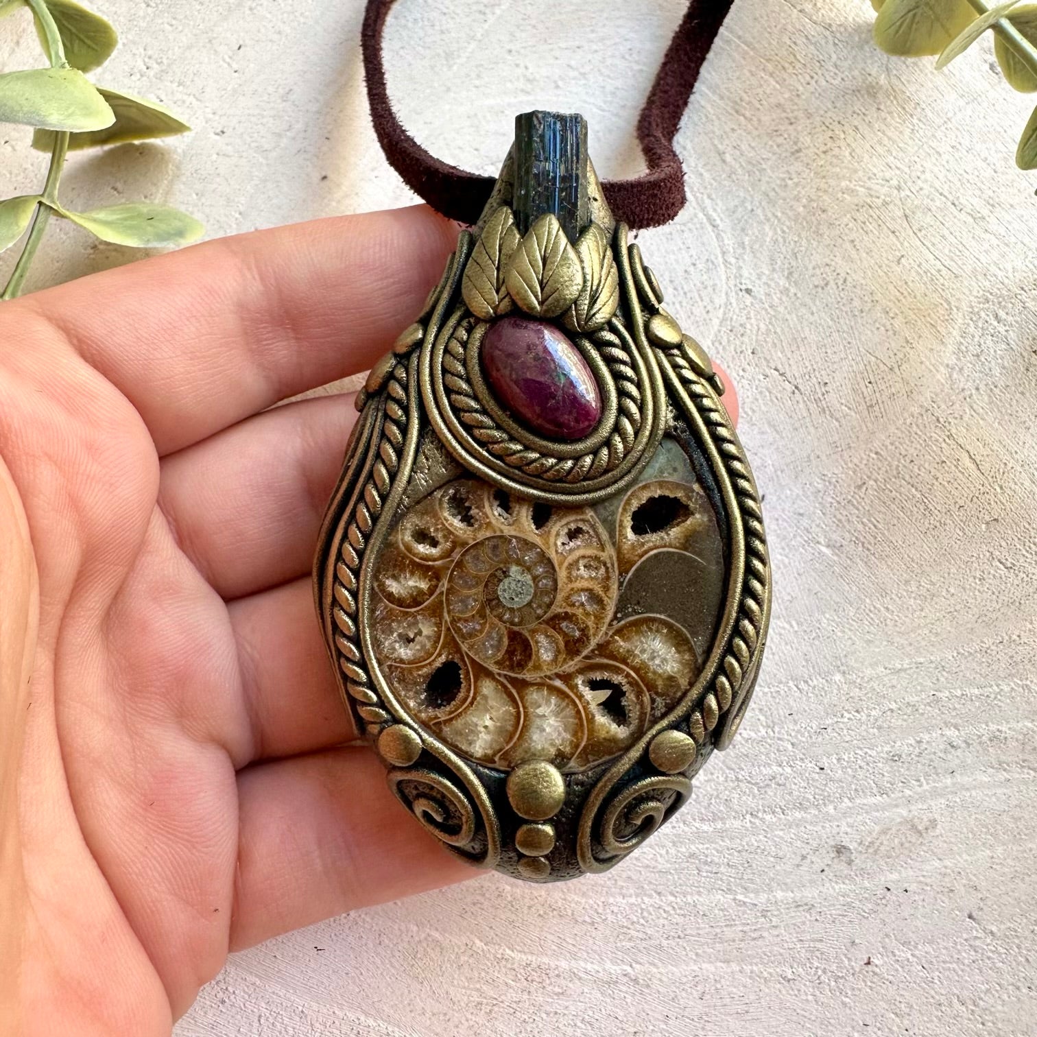 Natural Ammonite pendant featuring Black Tourmaline and a rich red Ruby gemstone.