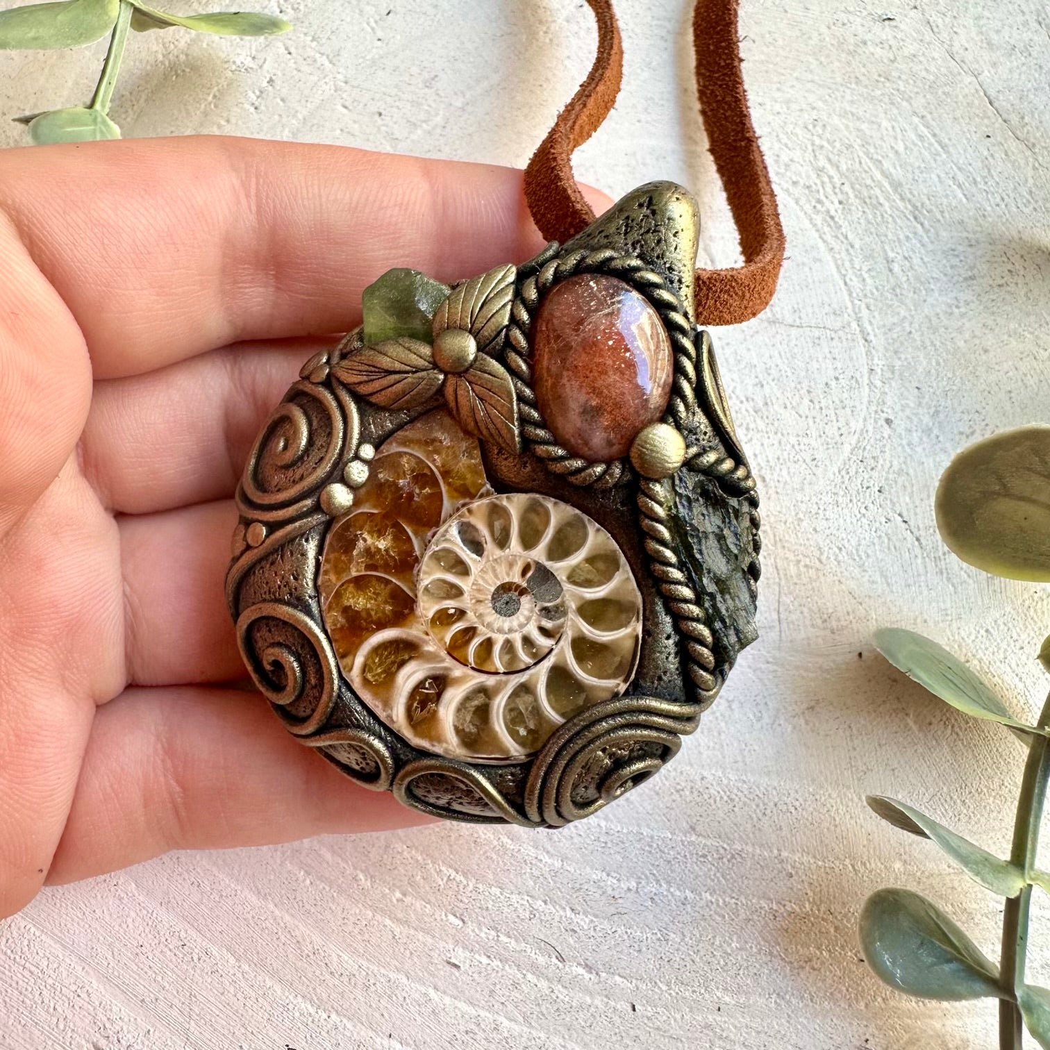 One of a kind pendant with a natural Ammonite fossil, glowing Sunstone and green gemstones.