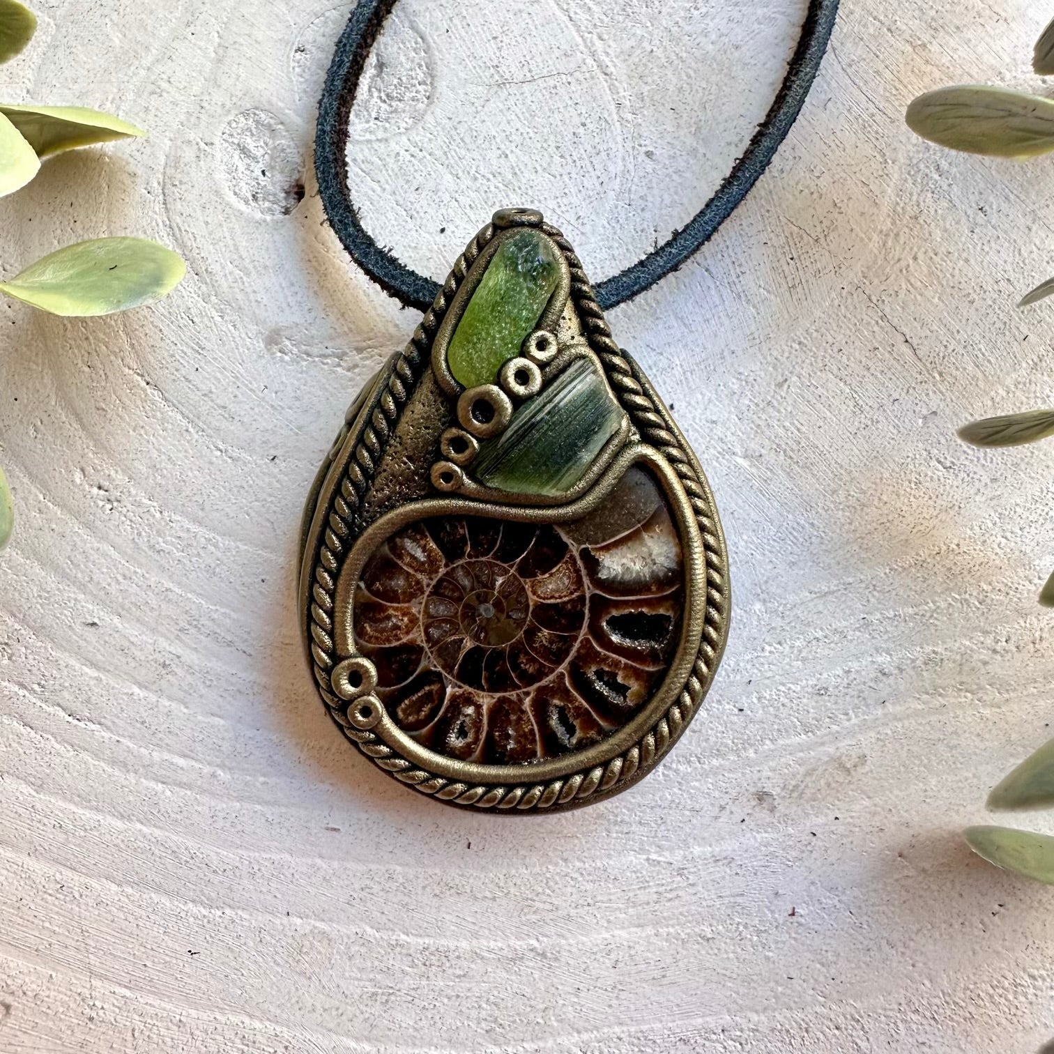 Handmade Ammonite necklace featuring Peridot and Moldavite, a one of a kind unisex gemstone jewelry piece combining an ancient natural fossil with vibrant green crystals. Artisan spiritual jewelry crafted with genuine natural materials, inspired by transformation, renewal, personal growth and ancient Earth energy.
